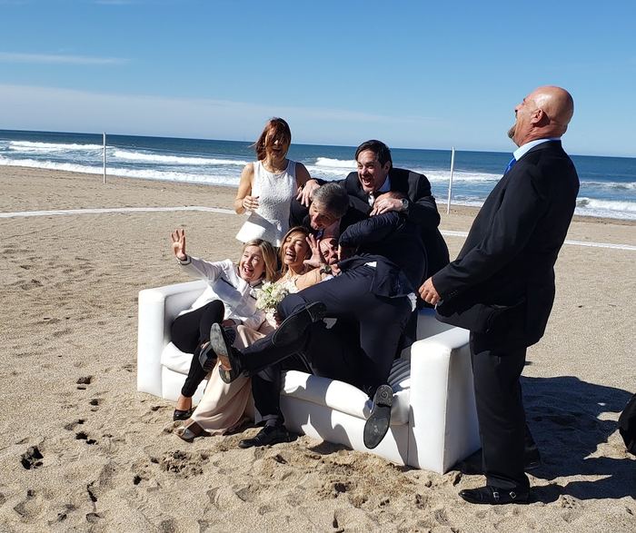 Novios y amigos en un sillón sobre la playa