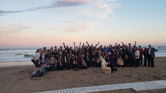 Invitados de casamiento festejando frente al mar al atardecer