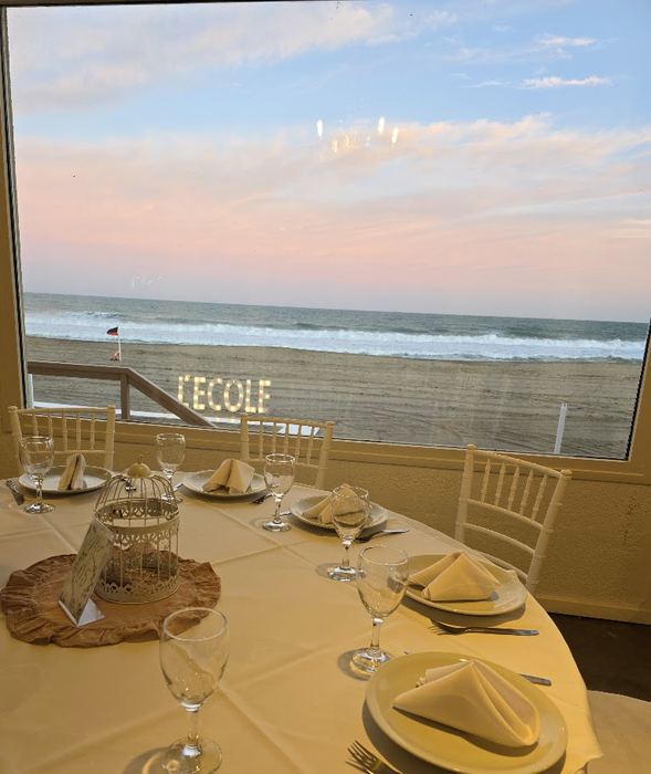 Mesa servida frente al mar con el cartel L´Ecole