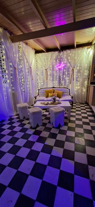 Rincón lounge con cortinas de luces y cartel de neón